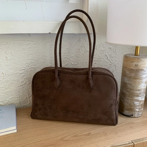Gros plan sur la texture en daim marron foncé lisse et les coutures robustes du sac à main