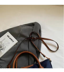 Dettaglio borsa a secchiello in nylon blu con manici in pelle marrone e tracolla regolabile