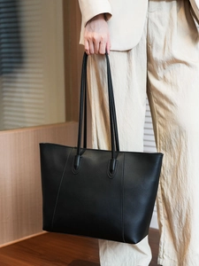Close-up of minimalist black leather tote bag featuring elegant vertical stitching detail