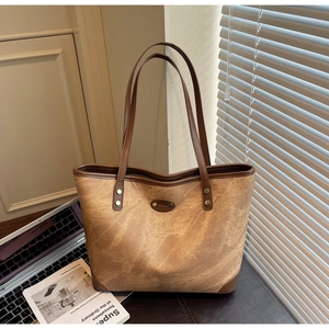 Detailed shot of retro brown tote bag with leather piping and vintage branding patch