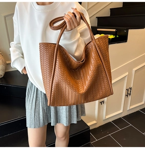 Close-up of the intricate cross-weave texture on the brown leather tote bag handle