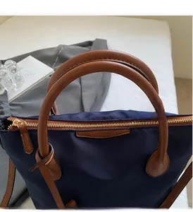 Dettaglio della borsa a secchiello in nylon blu con manici in pelle e zip dorata