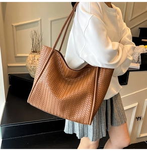 Detailed side view of brown woven leather tote bag shown in an elegant interior setting