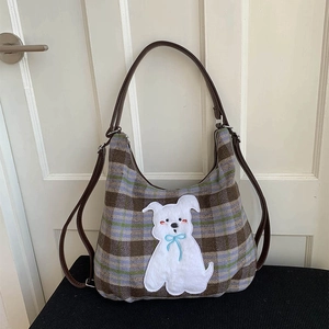 Close-up of British plaid wool tote with cute cartoon puppy patch and leather strap