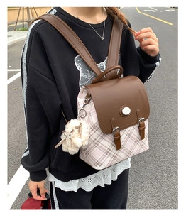 Detail of pink plaid canvas backpack with brown leather flap and side plush charm