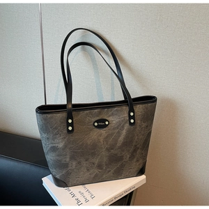 Close-up of marble pattern tote bag with leather straps and decorative logo plaque
