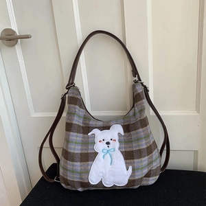 Detail of vintage plaid wool tote with embroidered puppy patch and leather straps