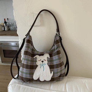 Detail of vintage plaid hobo bag featuring dog patch embroidery on fabric