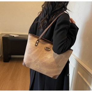 Side view of large tote bag with marble texture and leather trim on model in cozy room