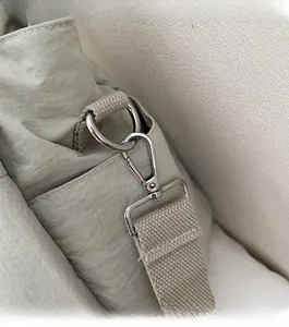 Macro detail of glossy silver metal swivel hook and light green nylon fabric shoulder strap