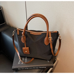 Vista dettagliata della borsa a secchiello in nylon con manici in pelle e logo sui libri
