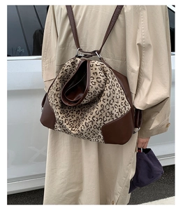 Detail view of leopard print backpack with brown leather trim worn with beige trench coat