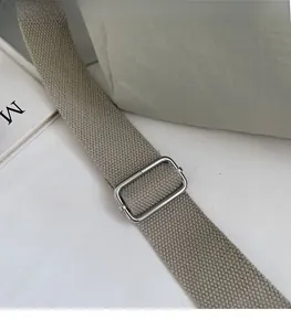 Close-up of adjustable shoulder strap with silver metal buckle on a canvas tote bag
