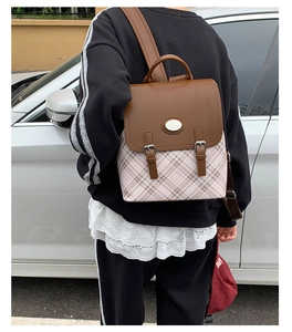 Rear view of model wearing a vintage plaid backpack with leather straps and metal buckles