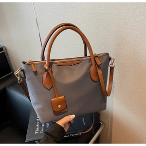 Dettaglio della borsa tote in nylon grigio-blu con manici in pelle marrone e tracolla rimovibile