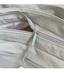 Detailed close-up of the smooth metal zipper and durable green nylon fabric on tote bag