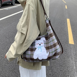 Plaid woolen tote bag featuring a cute plush dog patch shown in an outdoor street setting