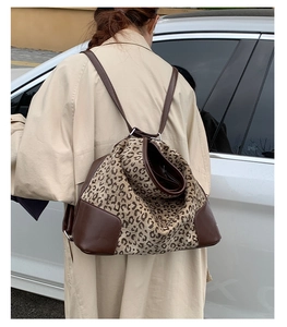 Detailed view of leopard print canvas backpack with premium dark brown leather stitching