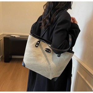 Close-up of a large tote bag with marble texture canvas and black leather trim details