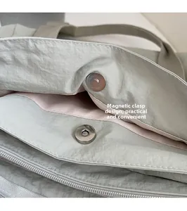 Detail of the magnetic snap closure and interior zipper pocket on a green tote bag
