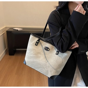 Detail of large tote bag with marble texture and black leather handles for commuting