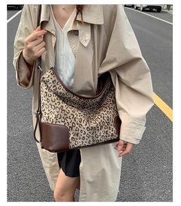 Close-up of leopard print tote bag with brown leather trim worn with a beige trench coat