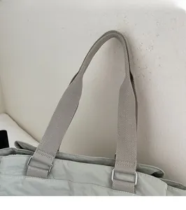 Detail of light green canvas tote bag with wide woven strap and silver D-ring buckle