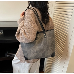 Macro view of a large vintage dark grey leather tote bag with black strap and reinforced base