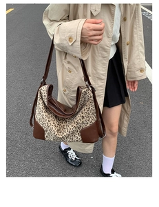 Detail view of leopard print canvas tote bag with brown leather trim and metal zipper