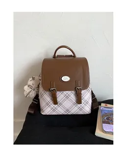 Detail of vintage college style backpack with pink plaid fabric and cute bear pendant