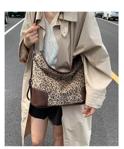 Street style view of large leopard print hobo bag with brown leather base and adjustable strap