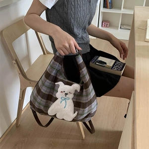 Close-up of plaid tote bag featuring a cute white puppy patch and brown leather handles