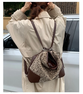 Leopard print backpack with adjustable leather straps worn by model in outdoor setting