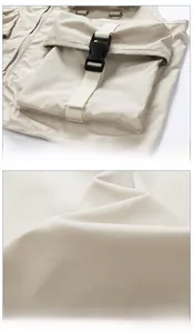 Détail du gilet tactique beige montrant une poche à rabat avec boucle et anneau en D