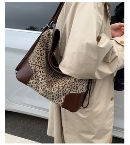 Street view of a large leopard print canvas hobo bag with brown leather strap detail