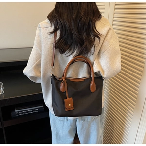 Vista posteriore della modella con borsa tote in nylon nero e manici in pelle marrone