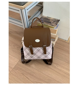 Close-up of vintage plaid backpack with brown leather flap and decorative metal buckle