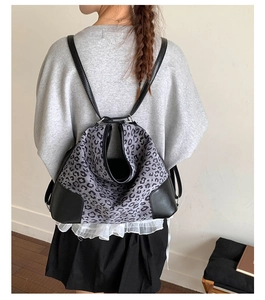 Detail of leopard print backpack with black leather trim and thin shoulder straps
