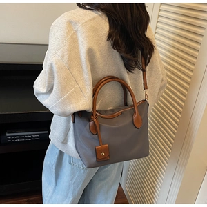 Secchiello in nylon grigio con manici in pelle marrone indossato da una modella in casa