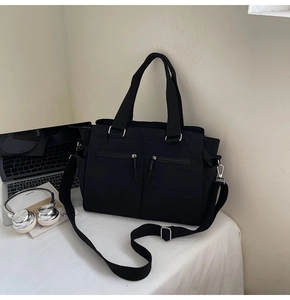 Detailed view of black nylon tote bag with functional multi-pocket design and silver hardware