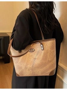 Retro brown large capacity tote bag with leather straps worn by model in warm indoor setting
