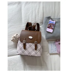 Detail of vintage plaid backpack with brown leather flap and cute cartoon patch