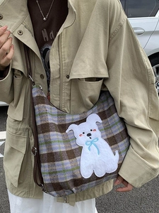 Plaid wool tote bag with plush puppy patch and adjustable leather strap in street style