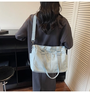 Rear view of a light blue large canvas tote bag with adjustable straps on a model
