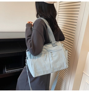 Close-up of sky blue nylon tote bag with functional multi-pocket design and wide strap