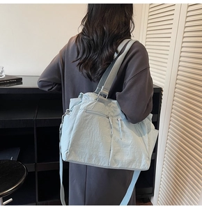 Detail of mint green tote bag with zipper front pockets and textured nylon material