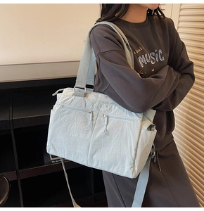 Detail of light blue nylon tote bag showing multiple zipper pockets and wrinkled texture fabric