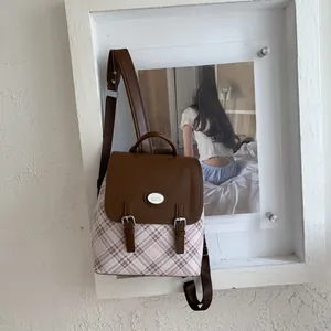 Close-up of vintage plaid backpack with brown faux leather trim and rabbit logo badge