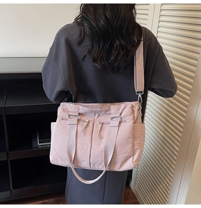 Detail of pink nylon tote bag showing multiple functional pockets and adjustable strap