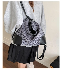 Detail shot of a grey leopard print backpack with black leather corners on a model